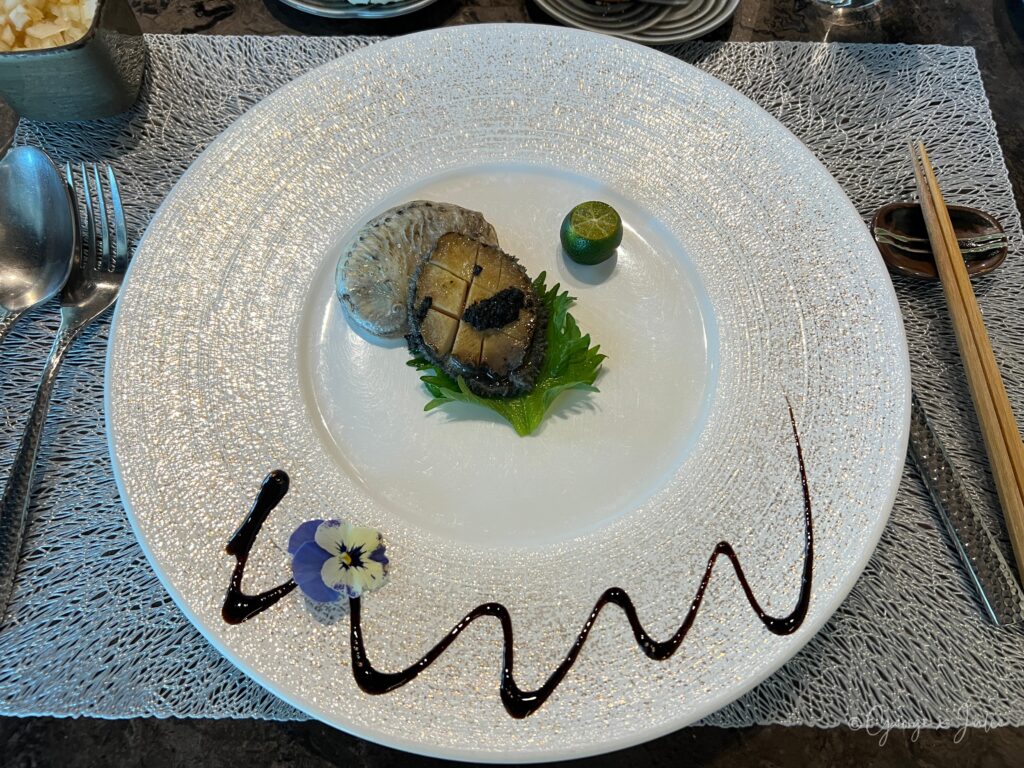 南非鮑魚佐奶油松露醬，半殼切花刀，搭配食用花與萊姆