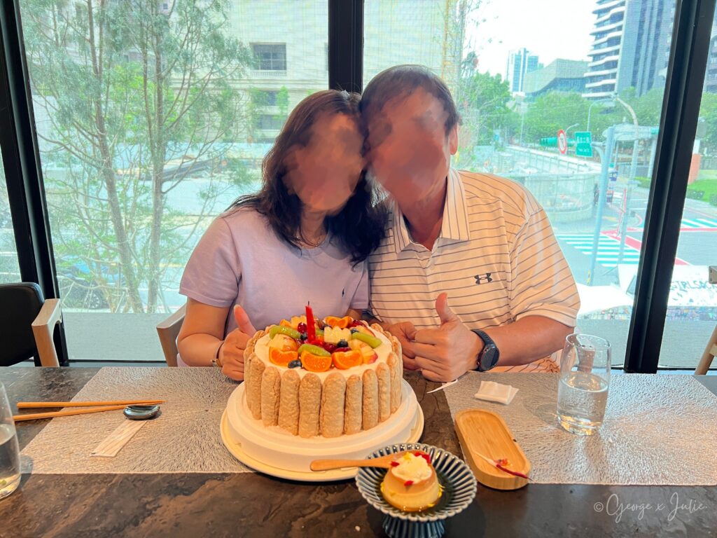 壽星媽媽和爸爸在生日蛋糕前合照，笑容燦爛