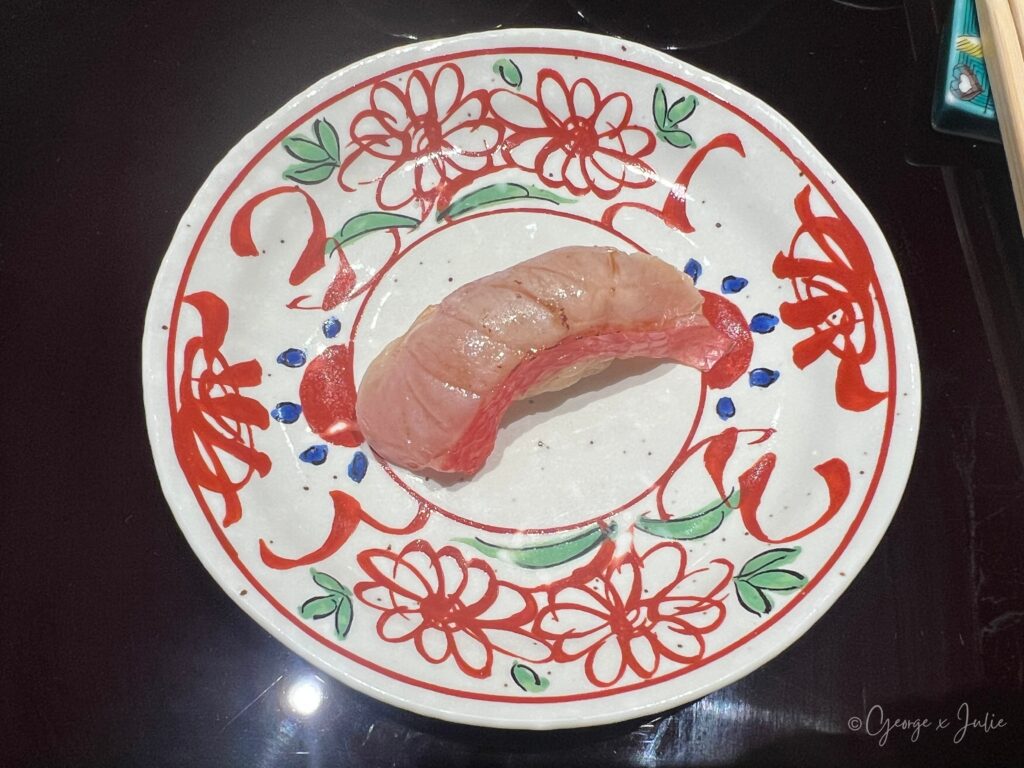 鮪魚握壽司，深粉紅色鮪魚肉，盛在紅花紋圓盤