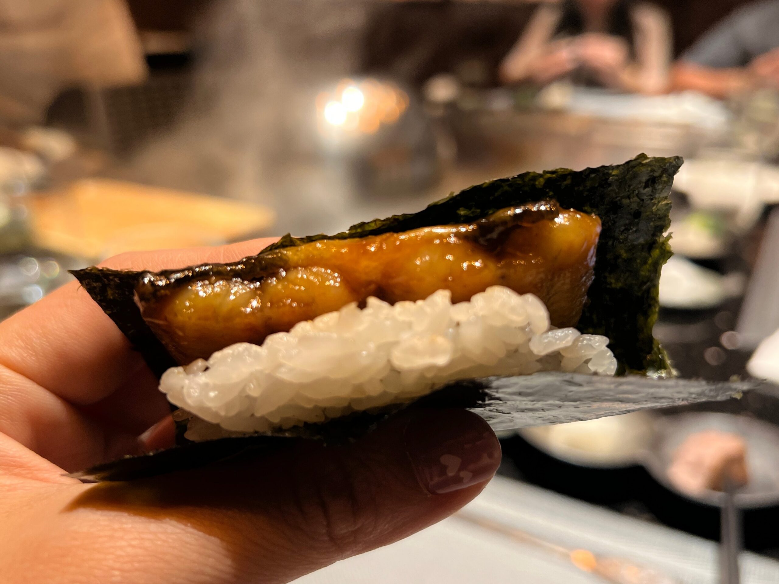 手拿海苔鰻魚飯糰，鰻魚照燒醬色澤油亮