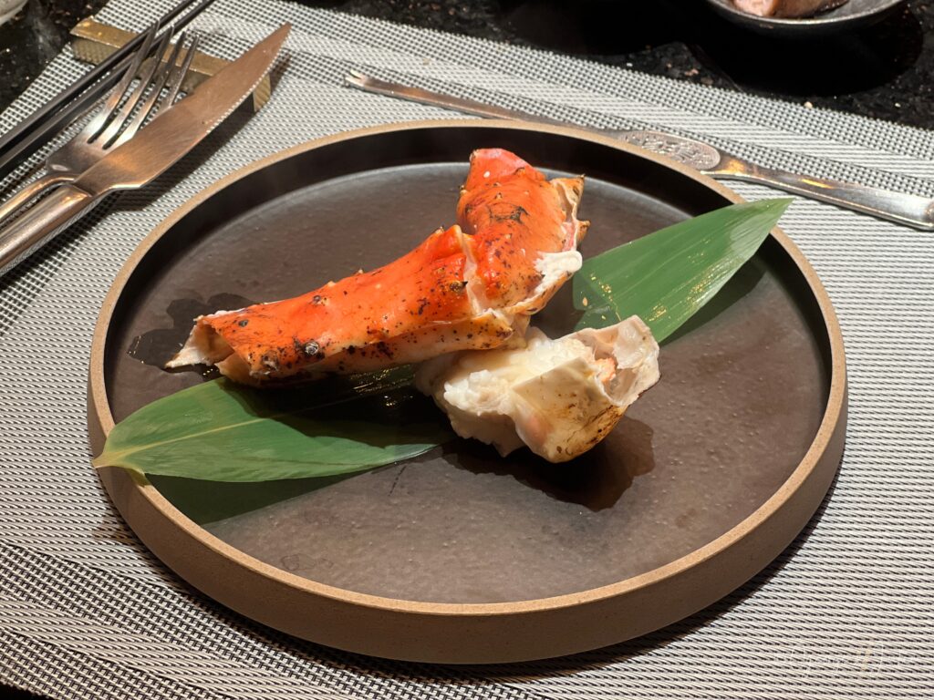 烤帝王蟹腳擺盤，蟹腳肉鋪在竹葉上