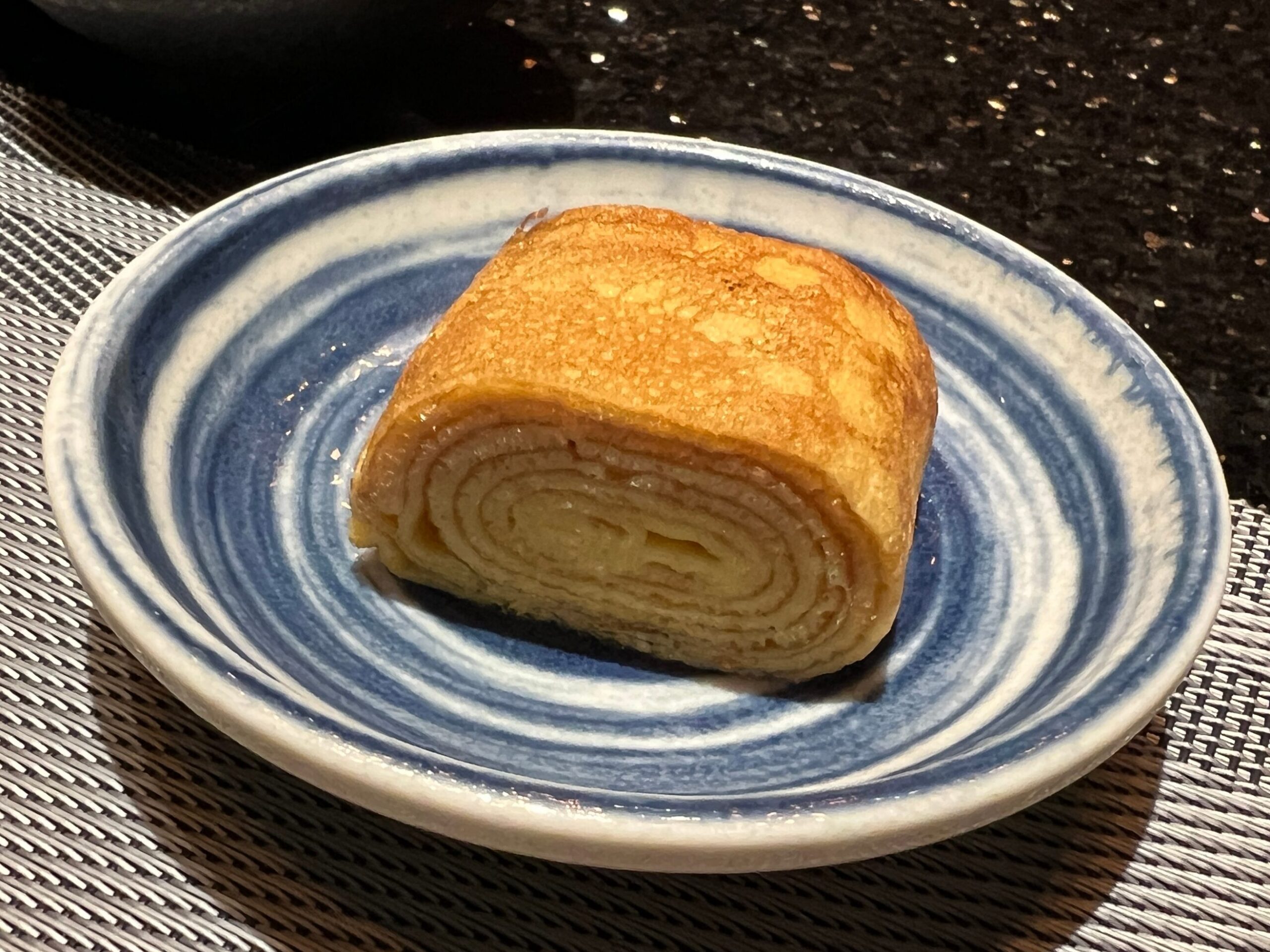 玉子燒切塊，金黃色盛在藍白漩渦盤