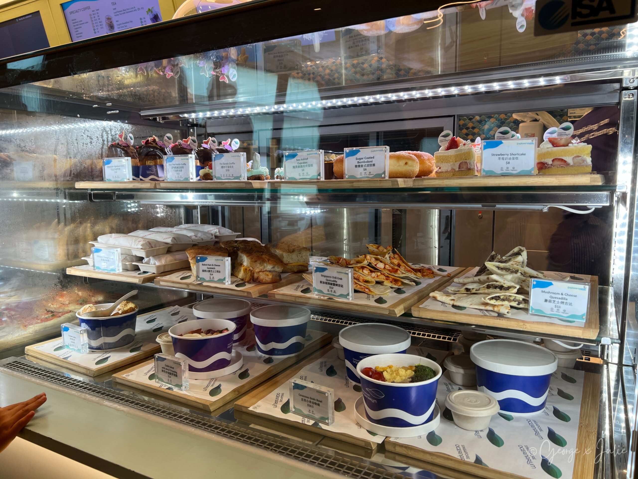 Explorer's Nook輕食櫃檯，玻璃展示櫃裡擺著蛋糕、三明治、沙拉等餐點