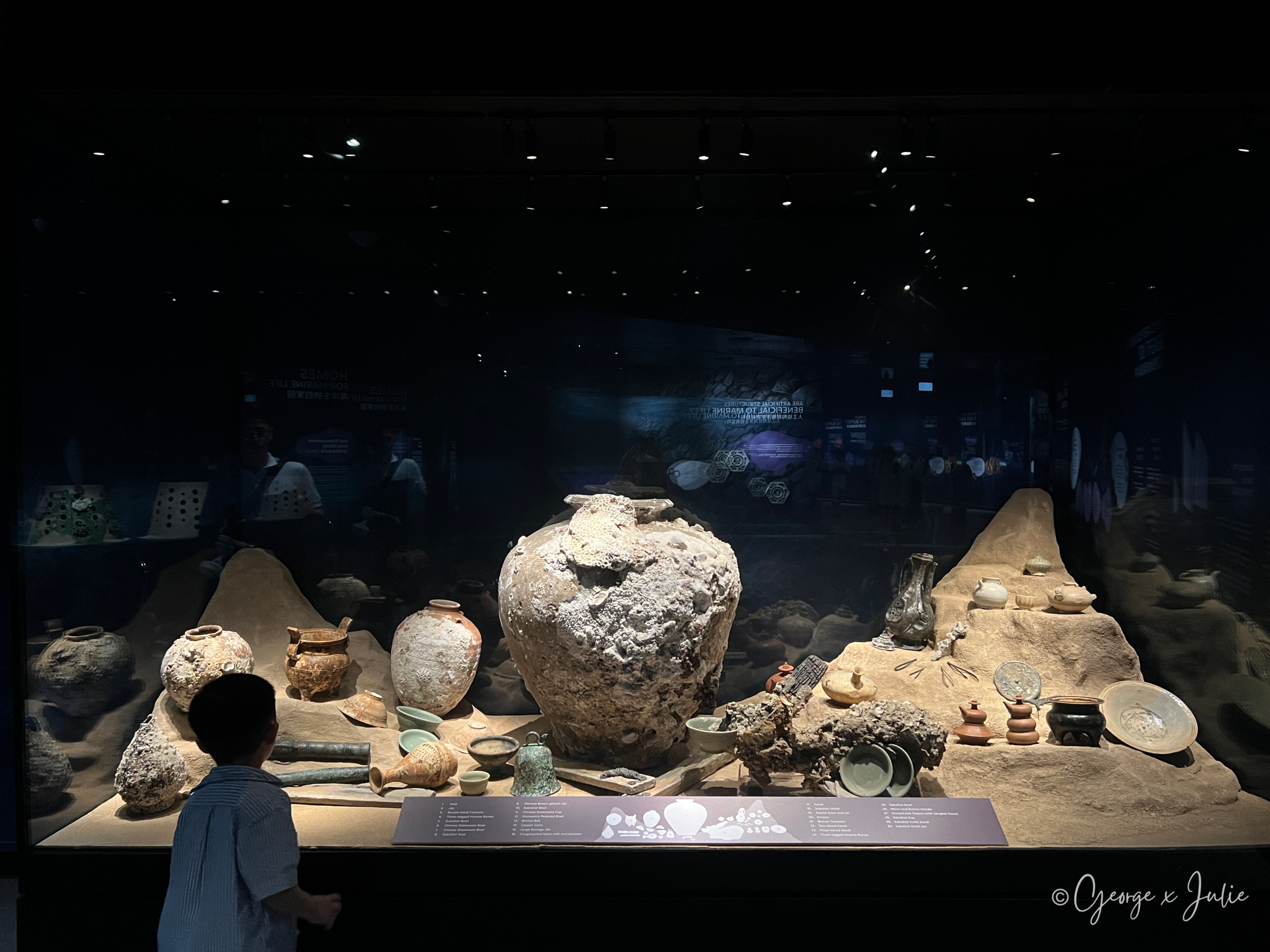 一整片古代沉船打撈文物展示，陶罐與瓷器上還留著珊瑚附著的痕跡