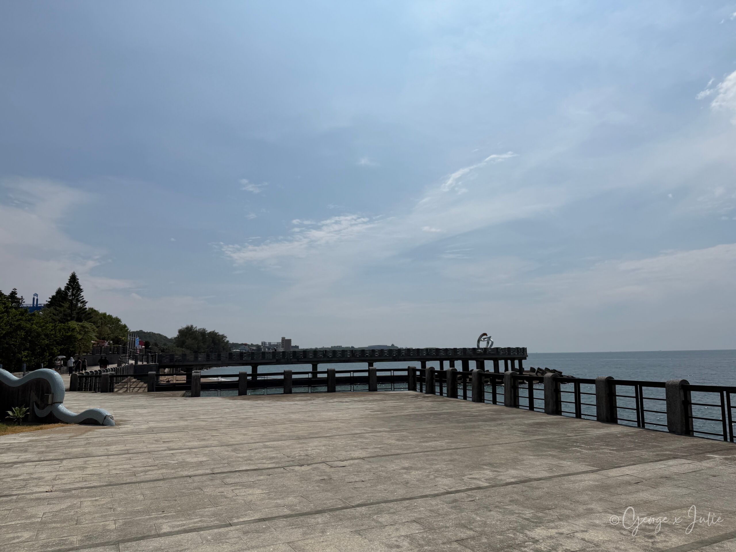 【新北三芝景點】芝蘭公園海上觀景平台|北海岸婚戒打卡海上步道 5 從海邊灶咖走往芝蘭公園海上觀景平台的步道,遠方可見延伸進海的平台與尾端裝置藝術,左側有白色波浪造型裝置牆