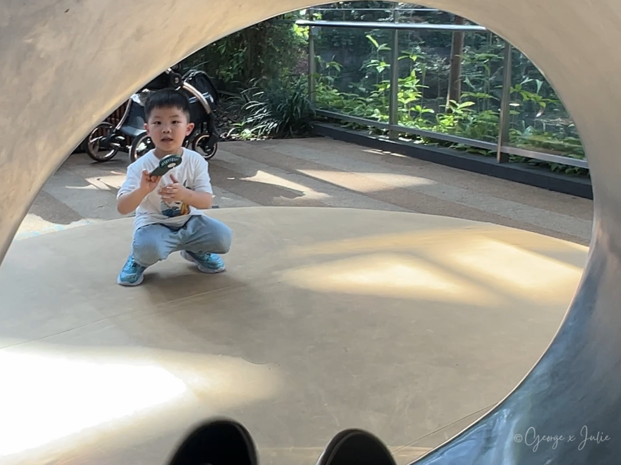 【新加坡親子景點】星耀樟宜星空花園Canopy Park|鏡子迷宮、天懸橋親子實玩攻略 22 從滑梯出口往外看,Jensen 蹲在軟墊上等媽媽溜下來