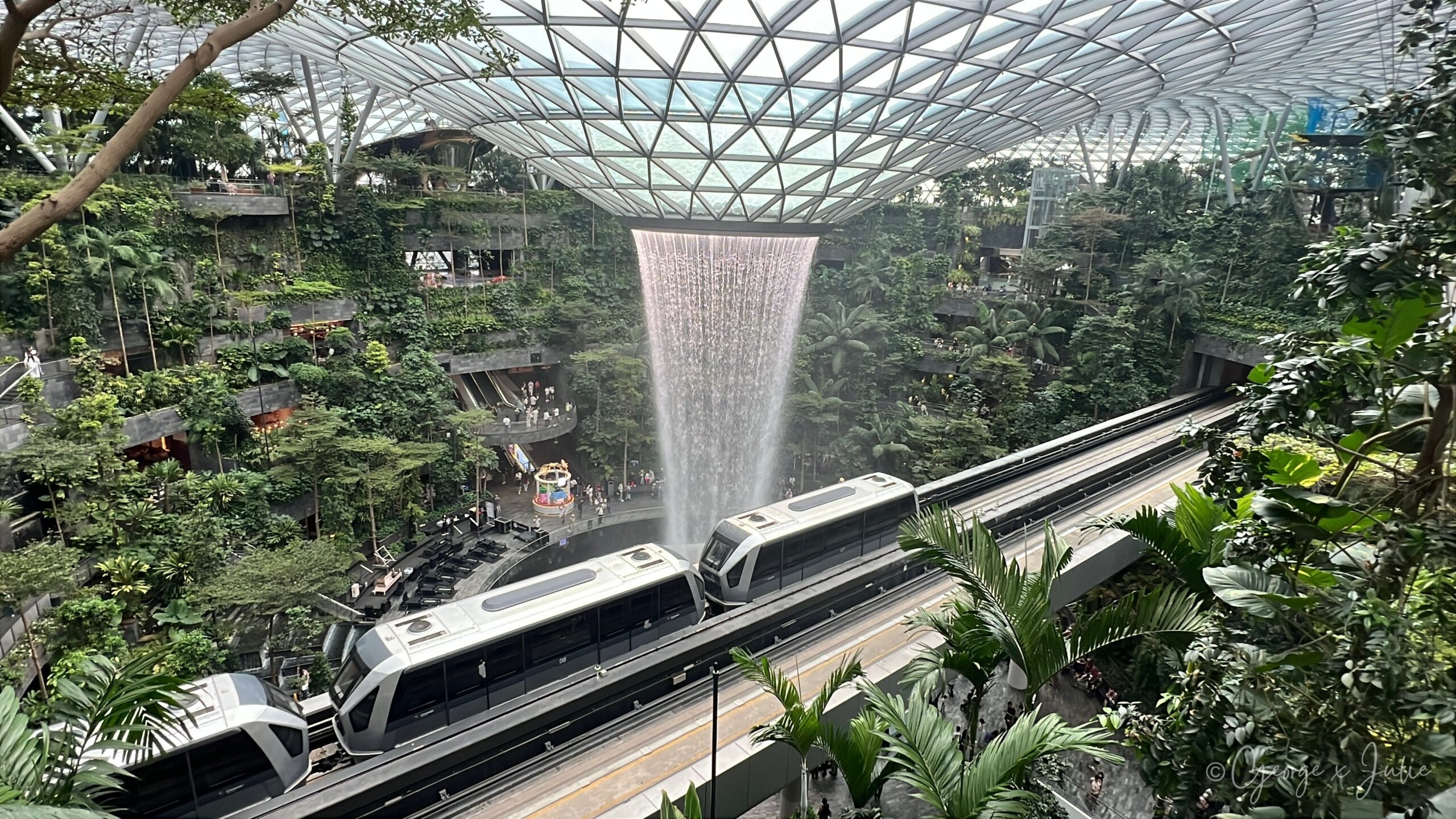 【新加坡親子景點】星耀樟宜星空花園Canopy Park|鏡子迷宮、天懸橋親子實玩攻略 1 從高層平台往下看,Rain Vortex 瀑布搭配架空列車呼嘯而過,這個角度也是星耀樟宜最經典的打卡視角