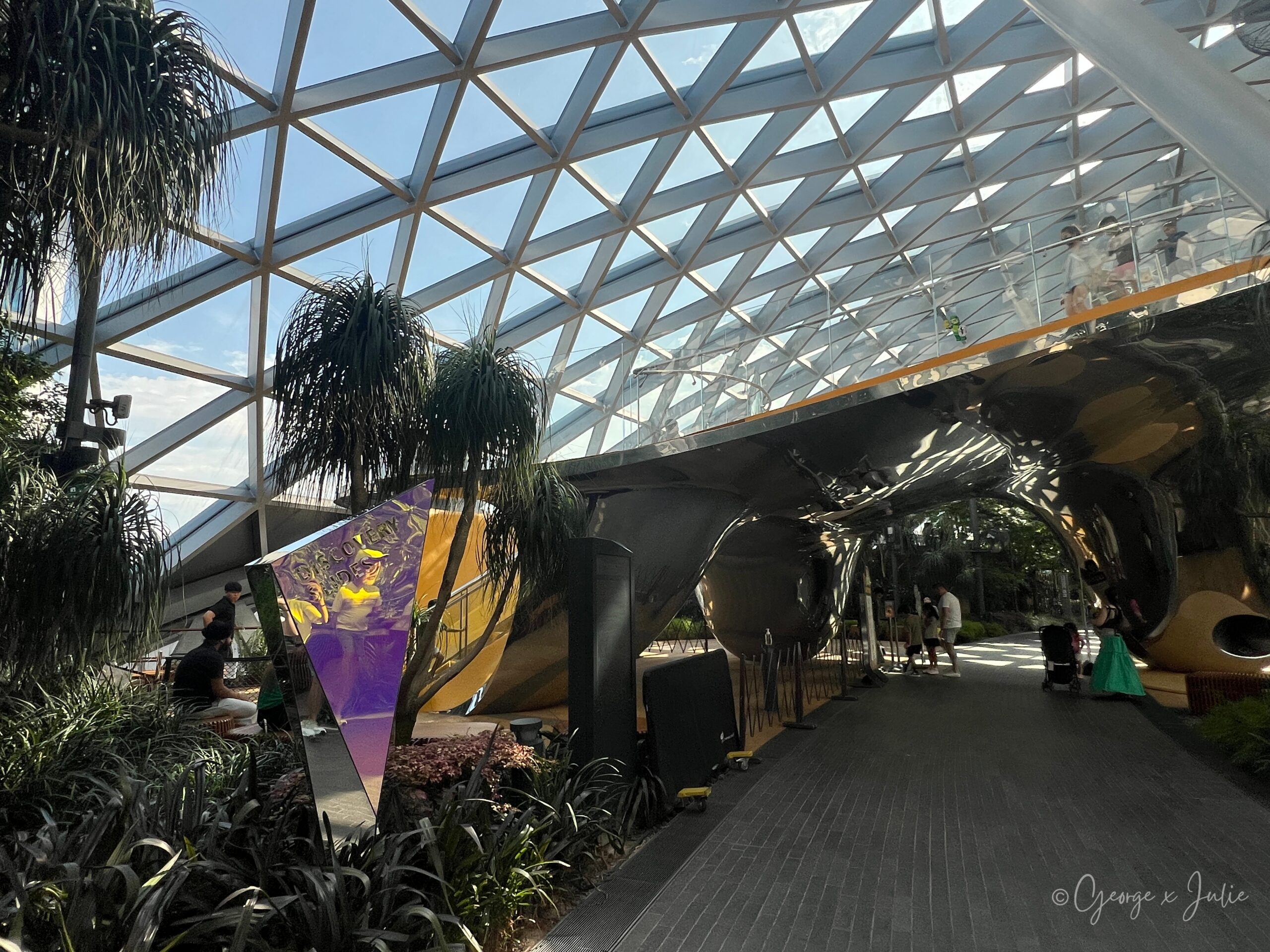 【新加坡親子景點】星耀樟宜星空花園Canopy Park|鏡子迷宮、天懸橋親子實玩攻略 20 DISCOVERY SLIDES(奇幻滑梯)的紫色鏡面招牌立在步道旁,銀色滑梯管道就在後方