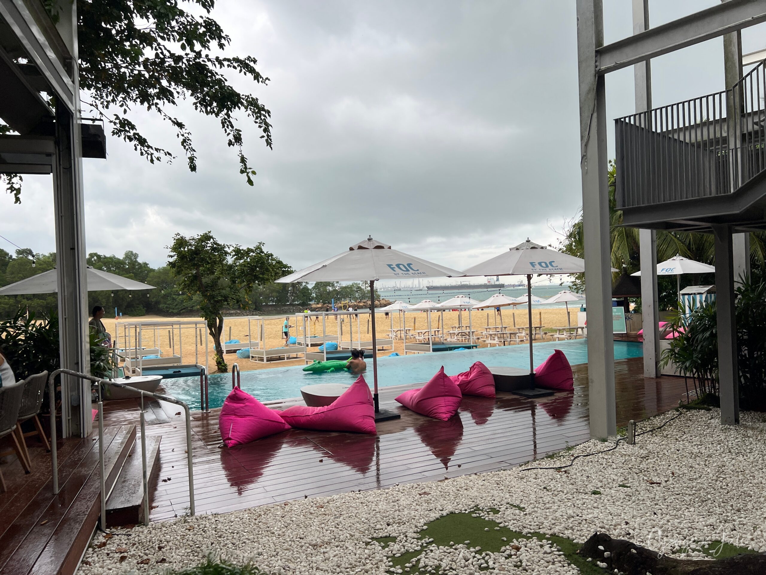 【新加坡美食】FOC by the Beach|聖淘沙Tanjong Beach泳池畔西班牙料理,親子海灘度假餐廳推薦 7 從室內望向戶外泳池與沙灘,粉紅懶骨頭沙發與FOC字樣遮陽傘