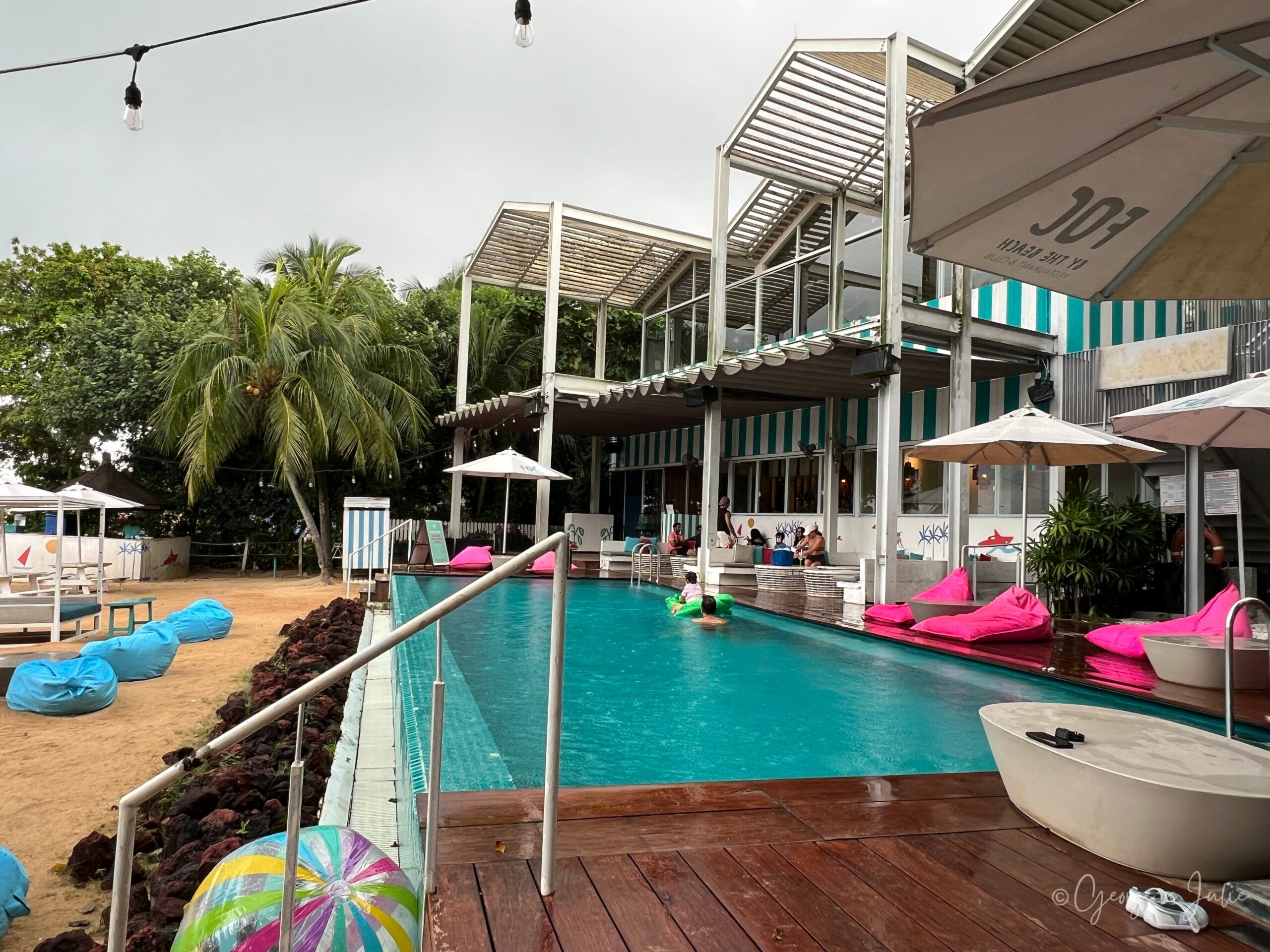 【新加坡美食】FOC by the Beach|聖淘沙Tanjong Beach泳池畔西班牙料理,親子海灘度假餐廳推薦 9 狹長泳池全景,有人拿綠色充氣鱷魚玩具戲水,一旁椰子樹