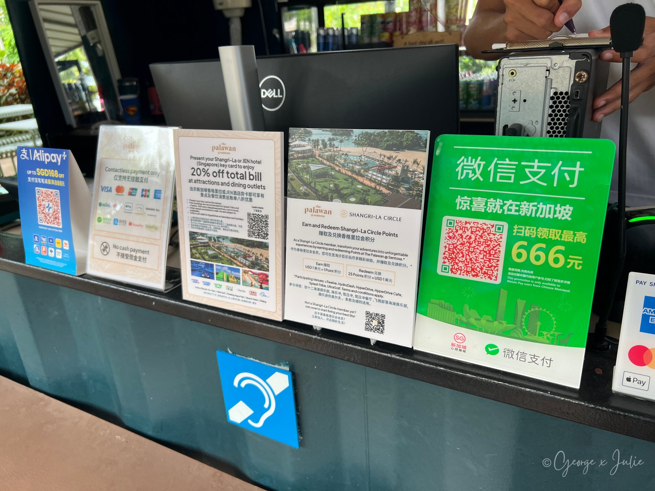 售票處櫃檯上的告示牌：出示香格里拉或 JEN 酒店房卡，園區景點與餐飲消費總帳單可享八折；另有香格里拉會員積分說明，以及僅支援非接觸式支付、不接受現金的提醒