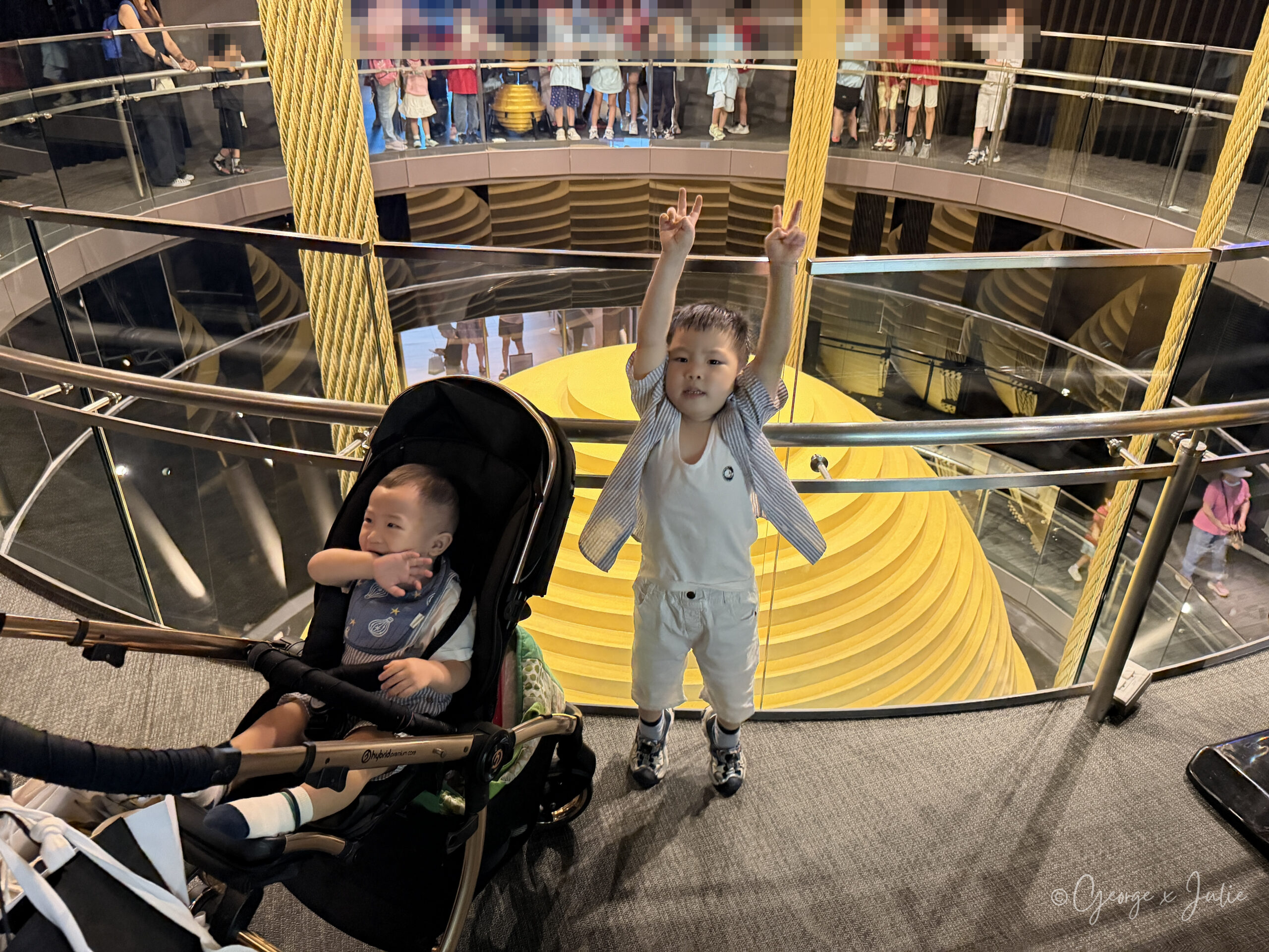 Jensen 在風阻尼球上方舉雙手比 YA，Morris 坐在旁邊的推車上