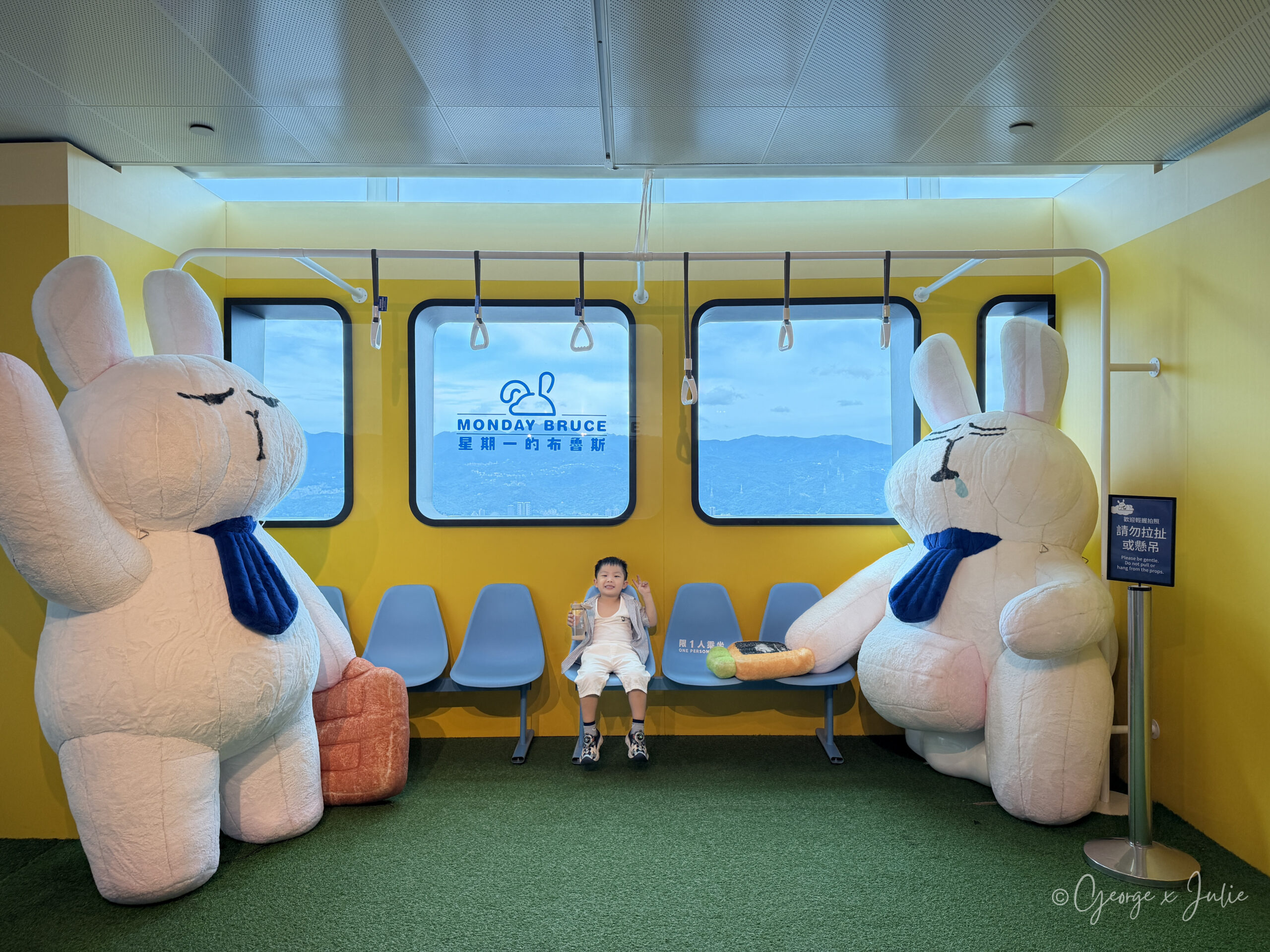 台北101觀景台布魯斯特展的黃色捷運車廂，Jensen 坐在兩隻布魯斯中間