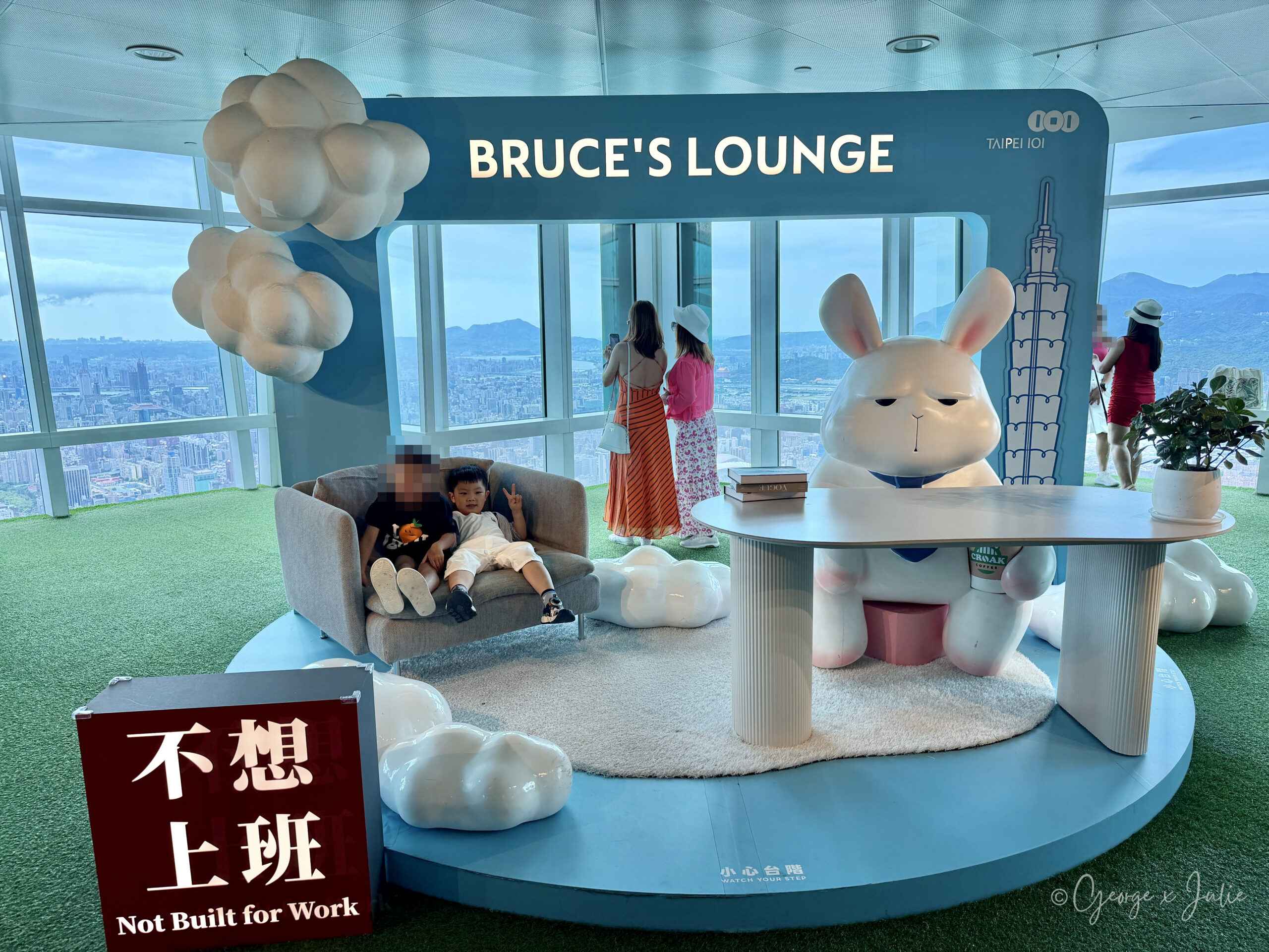 兩個小朋友躺在 Bruce's Lounge 的沙發上，旁邊是坐在桌前的大布魯斯