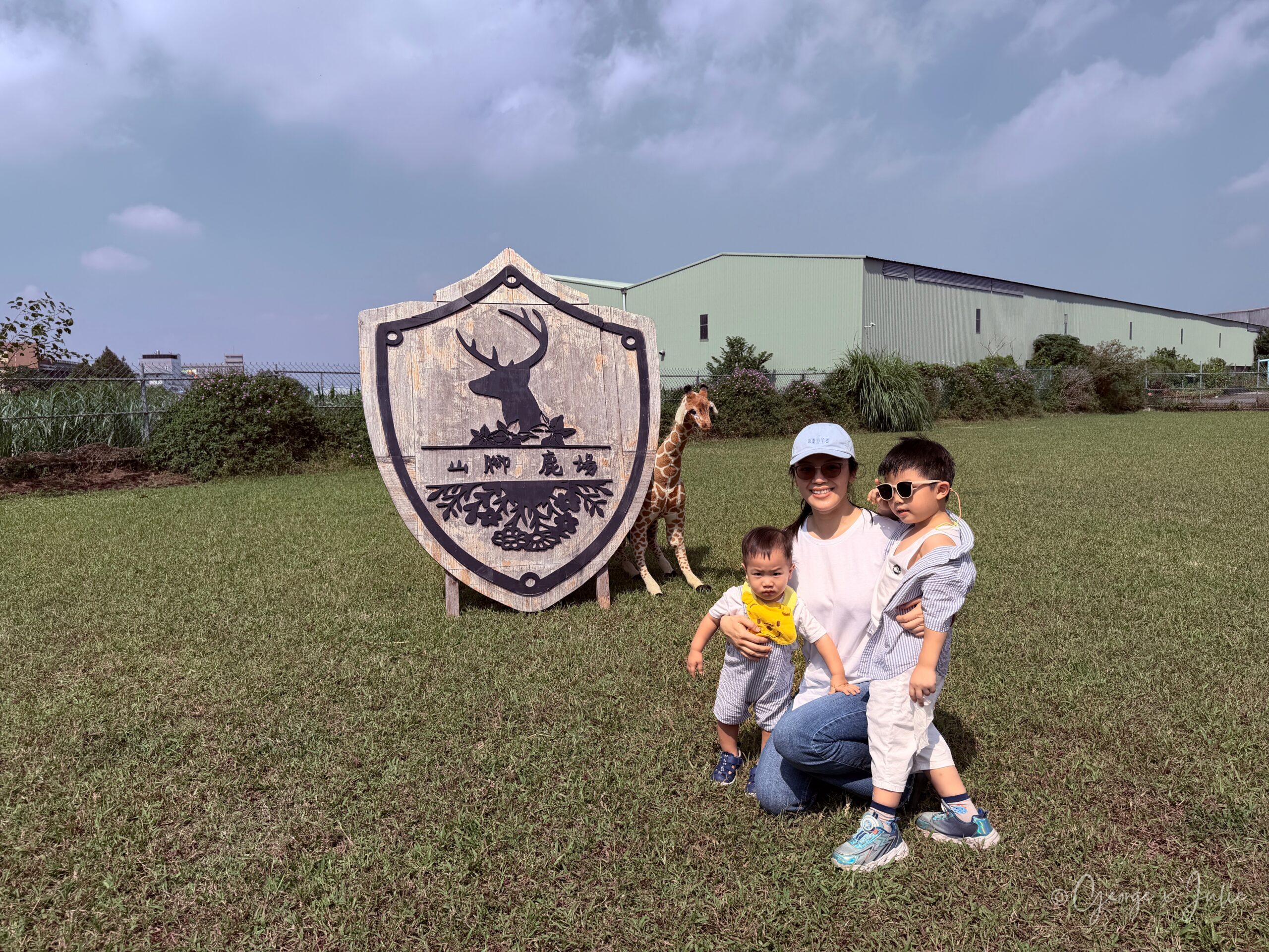 Julie 抱著 Jensen 和 Morris 在山腳鹿場招牌前合照